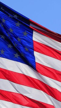 The flag of the United States of American blowing in the wind. Vertical video.