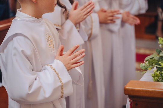 Little children in white communion dresses praying together in a church, first holy communion ceremony