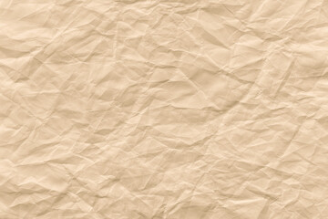 Fototapeta premium Crinkled beige paper texture background with soft, wrinkled folds.