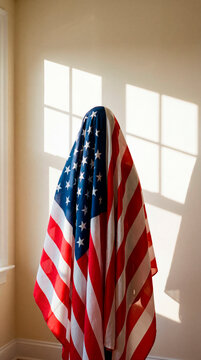 Faceless figure draped in American flag against sunlit interior wall
