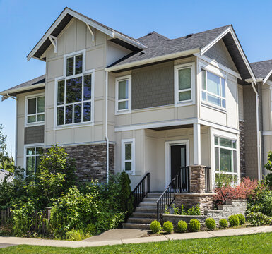 Entrance of a nice residential family house with green front yard. Walkout deck with patio area.