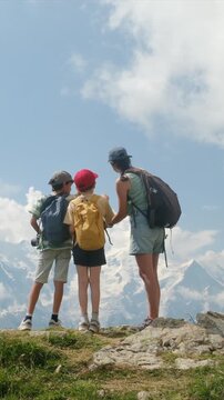 Mother teaching her two sons about the mountains during a family hiking trip, pointing towards the majestic snowy peaks of mont blanc in the beautiful european alps