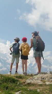 Mother and two sons hiking in the mountains enjoying the view of the snow-capped peaks, a perfect family bonding activity for an adventurous summer vacation