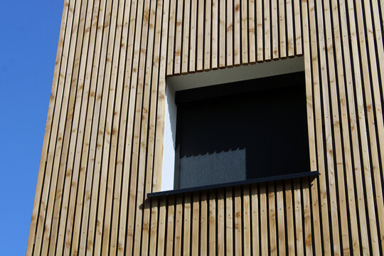B&acirc;timent &agrave; l&rsquo;esth&eacute;tique contemporaine avec bardage bois vertical et store de fen&ecirc;tre enrouleur occultant en toile tissu noir