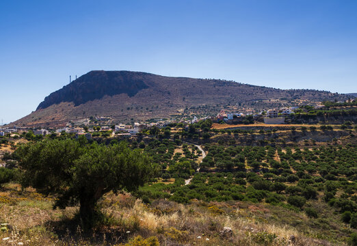 Scenic panoramic view of the traditional hillside village of Gouves in Crete, Greece, featuring the prominent Zoodochos Pigi church in the village center