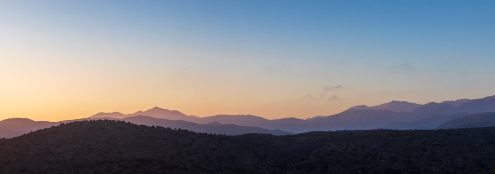 Beautiful sunrise over mountains in Crete, Greece, showcasing majestic layers of silhouetted hills under a colorful morning sky