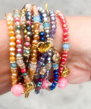 Close-up of colorful beaded bracelets with gold charms on a woman&rsquo;s wrist. Bright handmade jewelry, fashion accessories, boho style, crystal beads and summer lifestyle detail.
