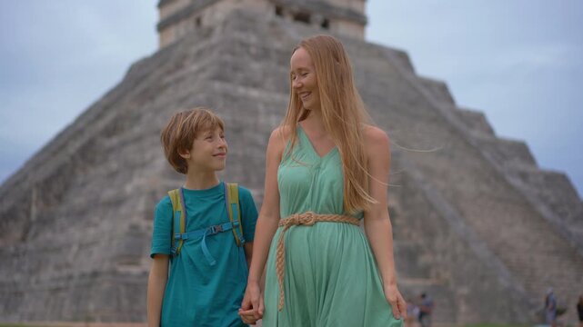 Happy tourists young mother and her little son walking in front of Kukulkan pyramid in Chichen Itza, Mexico. Slowmotion video.
