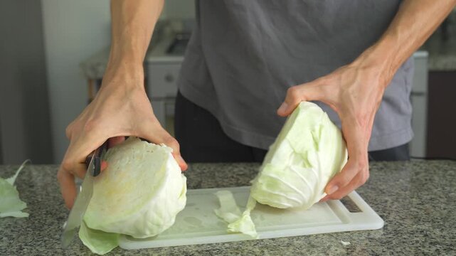 Close up man cutting cabbage with knife with clear sound. Hands slicing fresh vegetable on cutting board. Cooking preparation, healthy food, kitchen routine and ASMR concept.