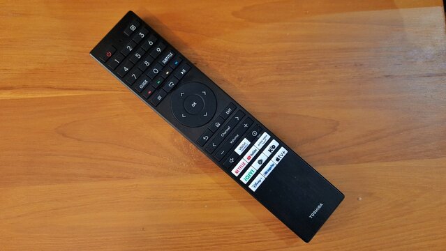 Banyuwangi, East Java, Indonesia - April 29 2026. Black TV Remote Control on Wooden Table
