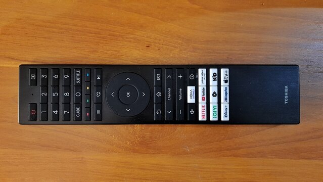 Banyuwangi, East Java, Indonesia - April 29 2026. Hand holding a black smart TV remote control with app buttons