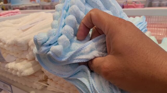 a person holding a stack of soft towels on display