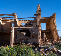 Fototapeta premium Destroyed historic building with exposed wooden beams and rubble in the old town ruins of Belchite under a blue sky