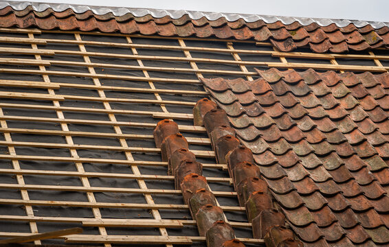 Clay roof tile repair and replacement on old house during roof renovation