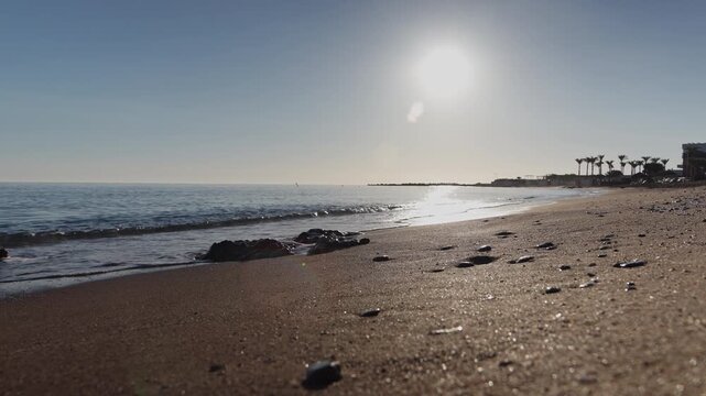 Panning video shot from Kato Gouves beach in Crete at sunrise, showing silhouettes of palm trees and buildings, turning towards the scenic open Mediterranean sea