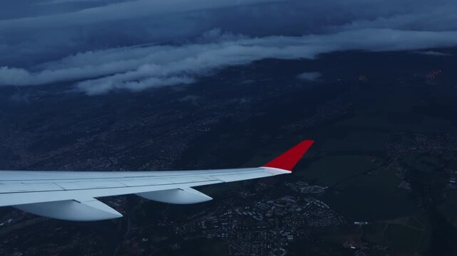 Dramatic aerial view of Prague city through an airplane window with airplane wing visible and dark storm clouds in the background. Concept of travel, bad weather flight and aviation