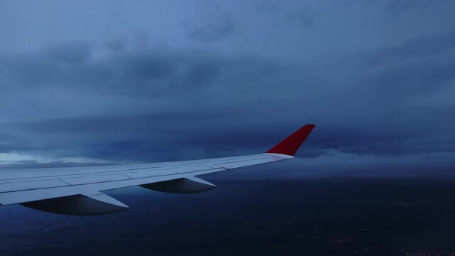 Dramatic aerial view of Prague city through an airplane window with airplane wing visible and dark storm clouds in the background. Concept of travel, bad weather flight and aviation