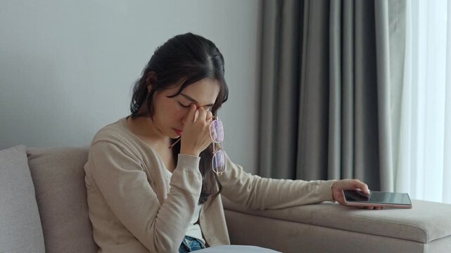 Young woman rubbing her eyes from using eyesight to relieve eye pain after using mobile phone