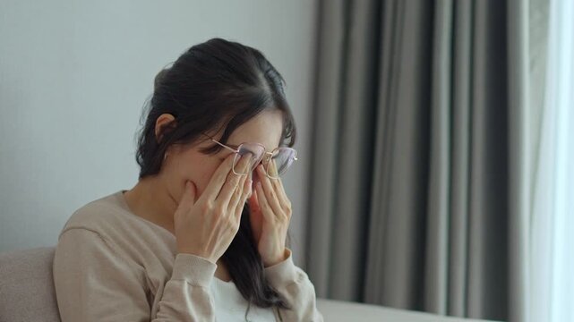 Young woman rubbing her eyes from using eyesight to relieve eye pain after using mobile phone