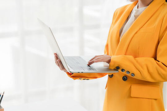 Professional Woman with Laptop: A confident business professional in a vibrant yellow blazer works diligently on a sleek laptop, embodying focus and modern efficiency.