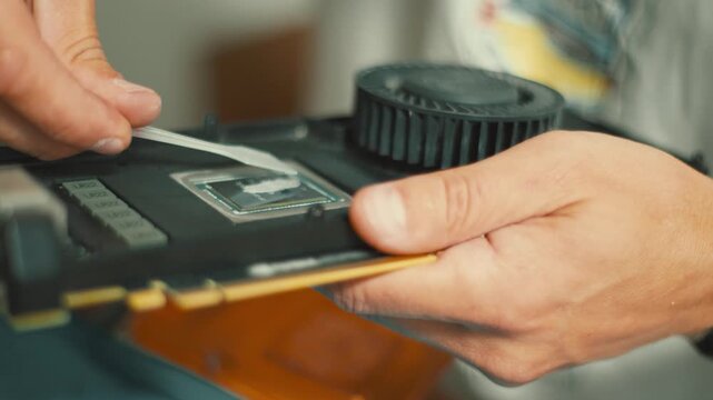 Technician applying thermal paste to graphics card gpu