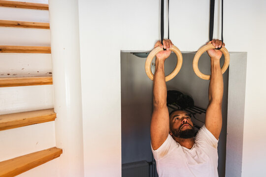 Man hanging and performing an exercise on gymnastics rings