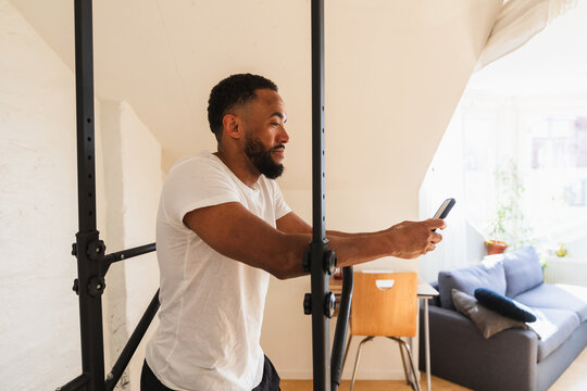Resting man checking smartphone at home workout station