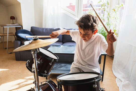 Energetic boy playing drums with passion and motion