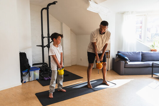 Father teaching young son how to lift kettlebells
