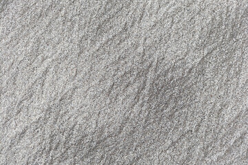 Obraz premium Coarse sand texture on the beach with broken seashell fragments. Dark coastal ground background with natural water erosion patterns.