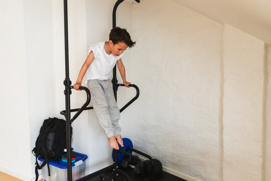 Active young boy practicing dips on home gym equipment