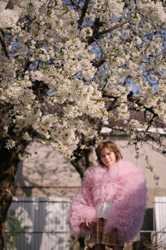 Little girl playing under blooming tree