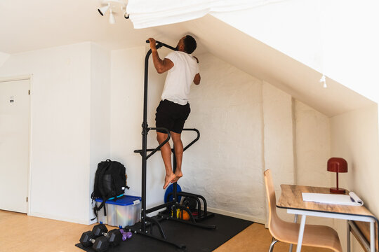 Man performing a back-view pull up at home power station