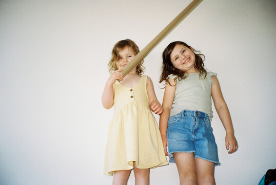 Two cheeky sisters standing on lounge playing imaginative games