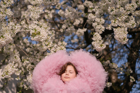Carefree girl in spring cherry blossom garden