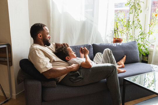 Relaxed father and son resting on sofa with phone