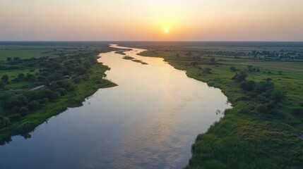 Fototapeta premium A Magnificent Sunset Paints the Sky with Golden Hues Over a Winding River Creating Stunning Reflections
