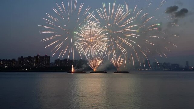 Launching three barges firing shells over dusk bay, showing fountains, smoke, reflections