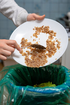 Scraping food waste from plate into a trash bin