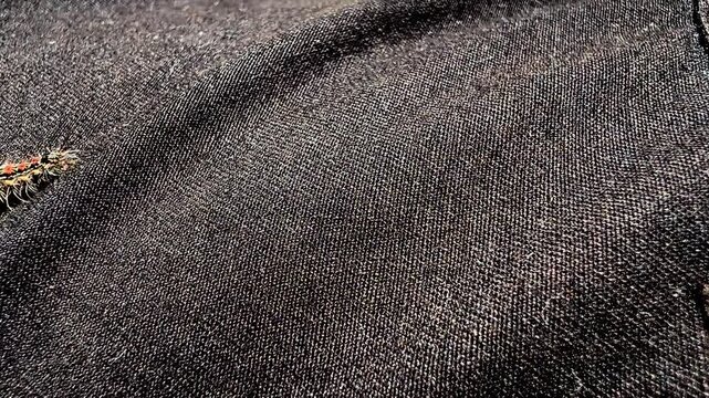 Hairy tussock moth caterpillar with red spots crawling on dark black denim fabric surface