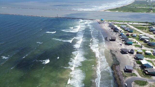 Jetty shoreline divides coastal homes near Seashell Dr sit beside Gulf roadway as long jetty separates open water from calmer inlet along barrier edge. Distinct roof tones, parcels, Freeport, TX