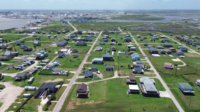 Surfside neighborhood spans residential rows east of Seashell Dr align RV lots open parcels while tank farms cranes rise across waterway. Mixed roofing, short term rental, vacations, Freeport, TX