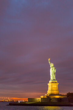 Statue of Liberty illuminated at twilight serves as a landmark destination for global travel and tourism on Liberty Island, New York City, USA.