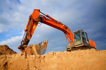 Excavator in ppen-pit mining. Digger on construction site on blue sky. Excavator moving soil. Heavy Machinery on mining in open-pit. Earthmover on earthmoving in sandpit. Groundworks  © MaxSafaniuk
