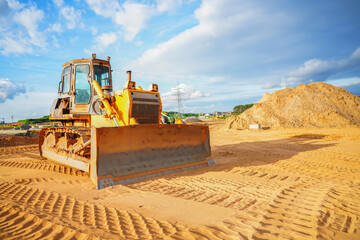 Bulldozer at road construction. Earth-moving equipment at road work, land clearing, grading, pool excavation, utility trenching. Dozer at construction site, utility trenching. Earth-moving machinery.  © MaxSafaniuk