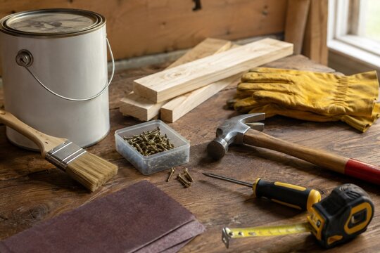 DIY woodworking tools and materials on rustic workbench with paint can brush hammer screwdriver and lumber