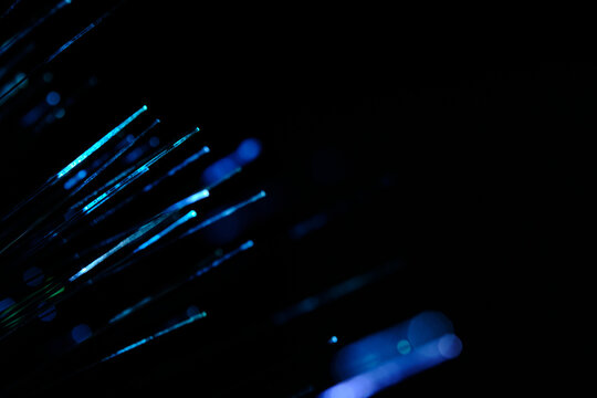 Diagonal blue and cyan glowing fiber optic strands extending out into deep dark space behind.