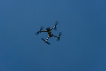 Quadcopter drone viewed from below against a clear blue sky © Natural Life Visuals