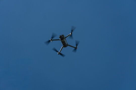 Quadcopter drone viewed from below against a clear blue sky