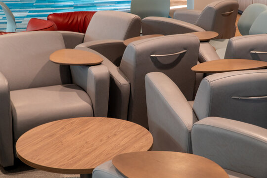 Modern lounge interior with comfortable grey leather armchairs and integrated wooden side tables, perfect for waiting areas, airport lounges, or contemporary office spaces.